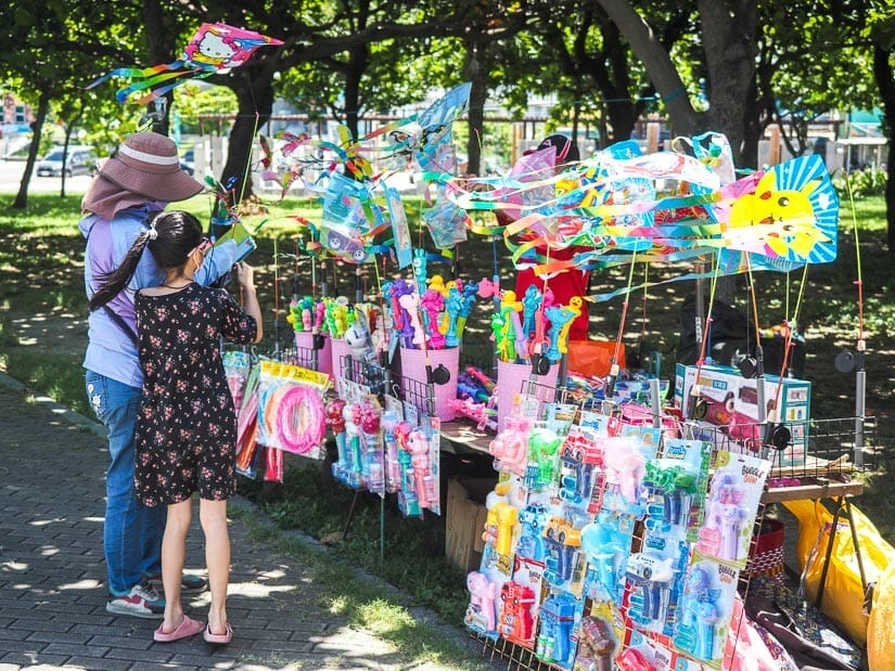 A kid buying something from a kite vendor at Cijin Windmill Park