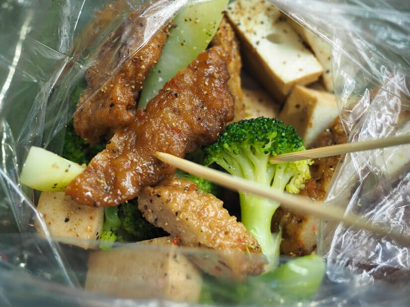Looking into a bag of luwei purchased at Guanghua Night Market, including broccoli, fish cakes, and more