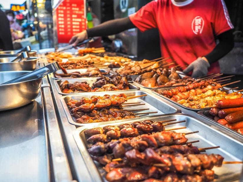 A food vendor selling sticks of barbecued meats in Jhongsiao Night Market