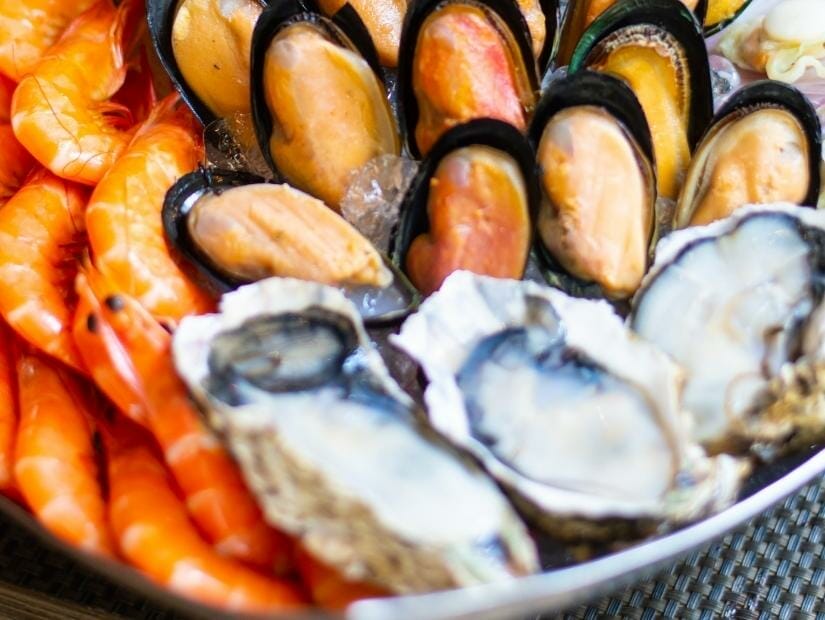 A bowl filled with oysters, abalone, and shrimps ready to be cooked in hot pot