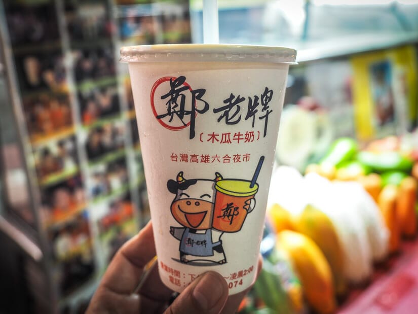 A hand holding up a cup of papaya milk at Liuhe Night Market in Kaohsiung