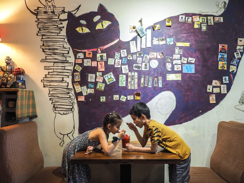 Two kids sharing a slushy drink at Mask Cat Cafe in Taipei
