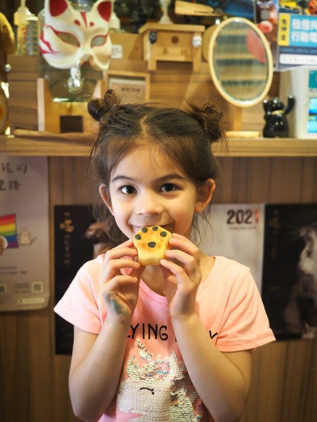 A girl holding up a cake shaped like a paw at Nezo Cafe in Taipei