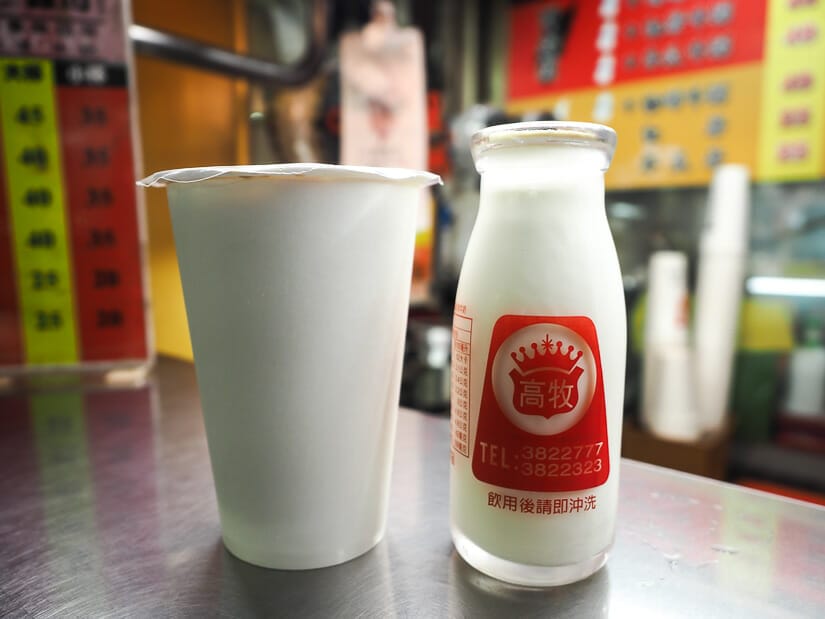 A cup of milk tea and a small bottle of milk beside it at a drink stall in Ruifeng Night Market