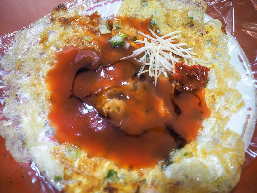 A large oyster omelet with sauce on it from a food stall in Ruifeng, the most popular night market in Kaohsiung among local youths