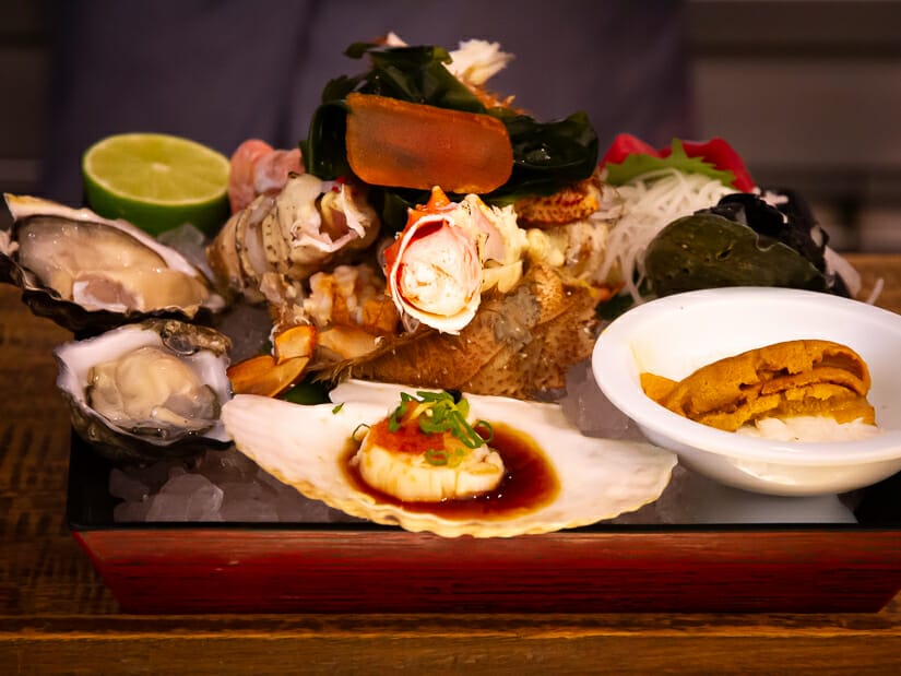 A large set meal of many seafoods on a wooden bar counter at Addiction Aquatic's Seafood bar