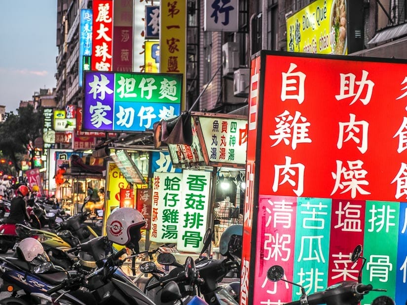 Neon signs and parked scooters at Guanghua Night Market