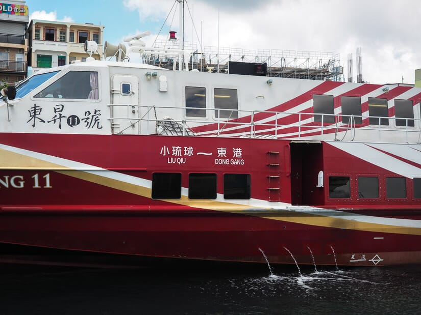 A maroon and white ferry that says Donggang to Liu Qiu on the side