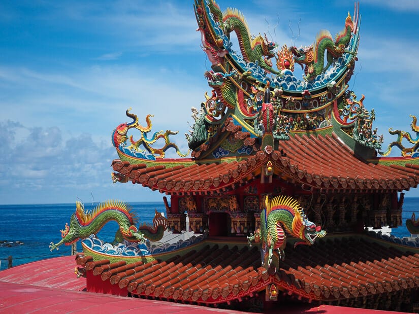 An elaborate, colorful temple roof on Lambai Island, with the ocean in the background