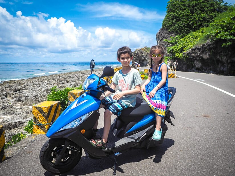 Two kids sitting on a scooter parked on the coast of Xiaoliuqiu