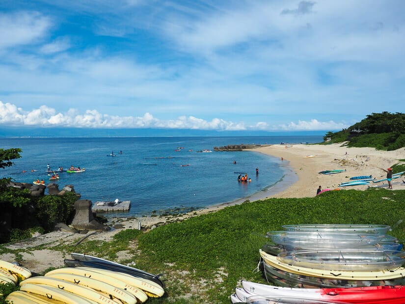 Expansive view of Zhongao Beach, the longest beach on Xiaoliuqiu, with many boats sitting in the grass beside the beach