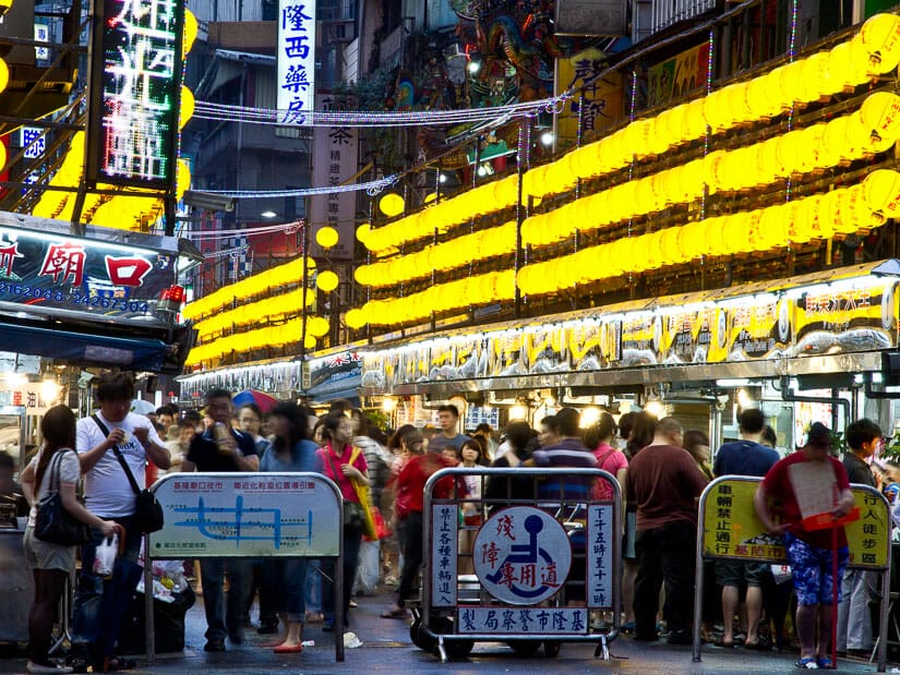 Entrance to Keelung Night Market, with crowds of people, food stalls on either side, and yellow lanterns above