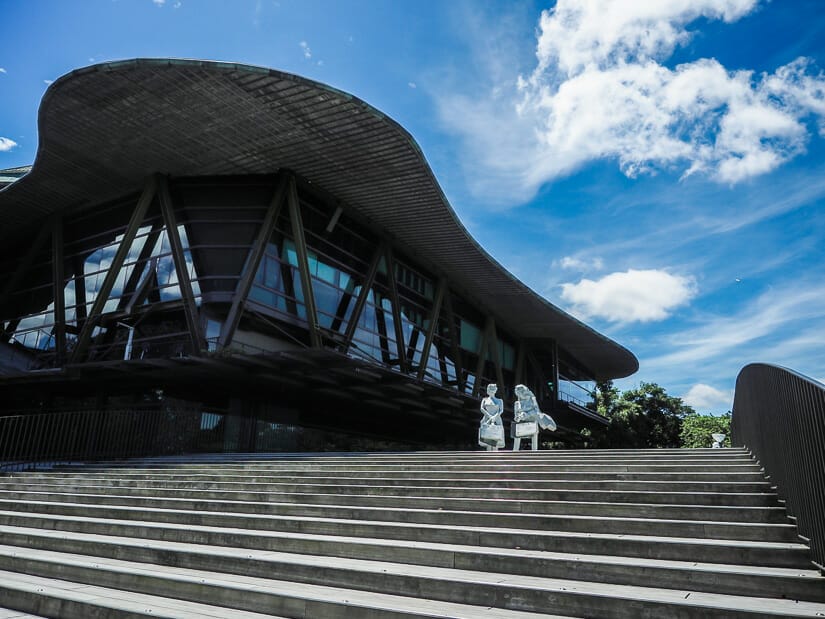 Looking up a staircase at Cloud Gate Theater in Tamsui, with two white statues of women walking down the stairs