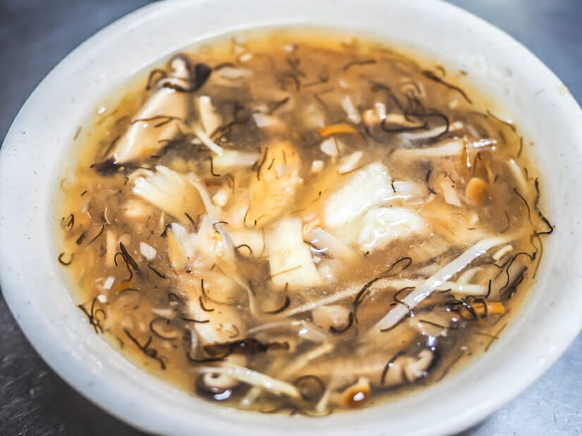 Close up of a bowl of crab sour with strands of bamboo and fungus in it at Keelung Miaokou Night Market
