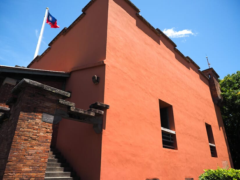 Red outer wall of Fort Santo Domingo in Tamsui and Taiwanese flag at top of pole