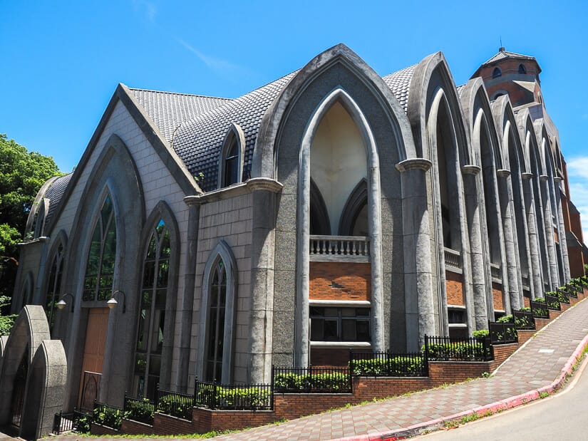 The exterior of a church at Aletheia University in Tamsui, with a sidewalk running along it uphill