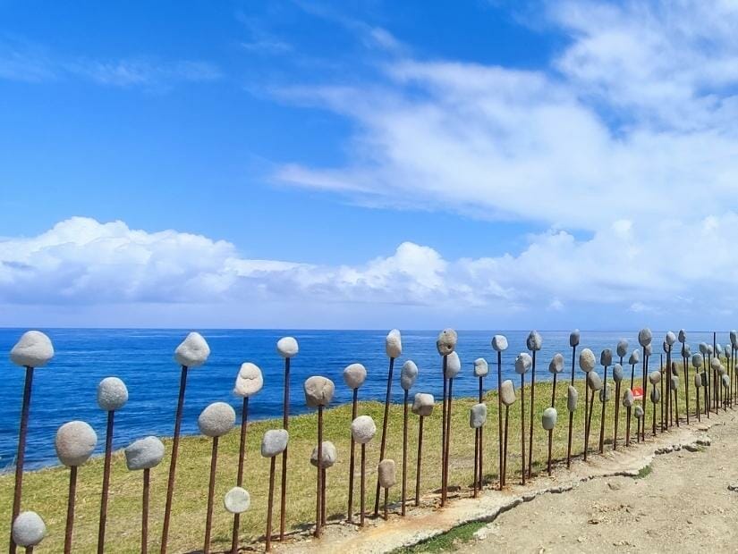 An art installation consisting of a row of metal rods, each supporting a pebble, with the ocean in the background at Jialulan in Taitung