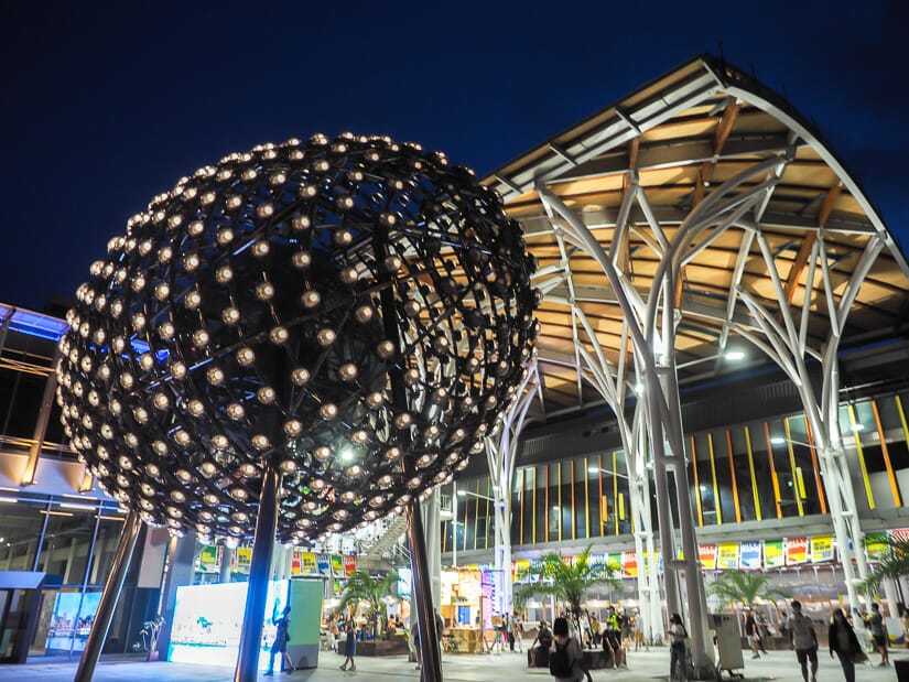 An art installation that looks like a giant egg with lights on it in front of Keelung Train Station at night