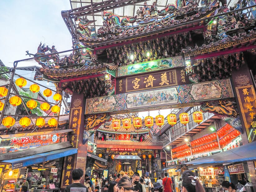 Entrance gate to Dianji Temple, with lots of people shopping in Miaokou Night Market below