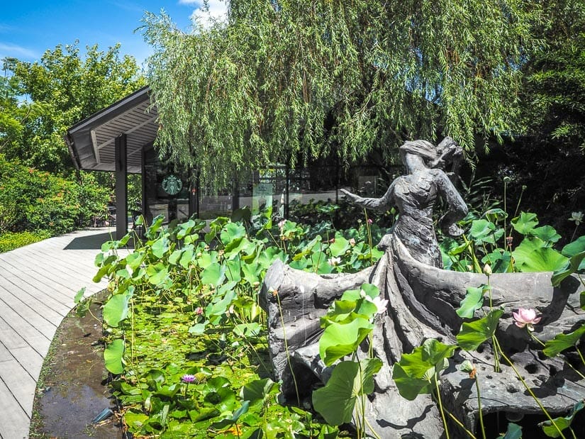 Statue of a woman in dress twirling inside a lotus pond in front of Starbucks Cloud Gate Theater branch