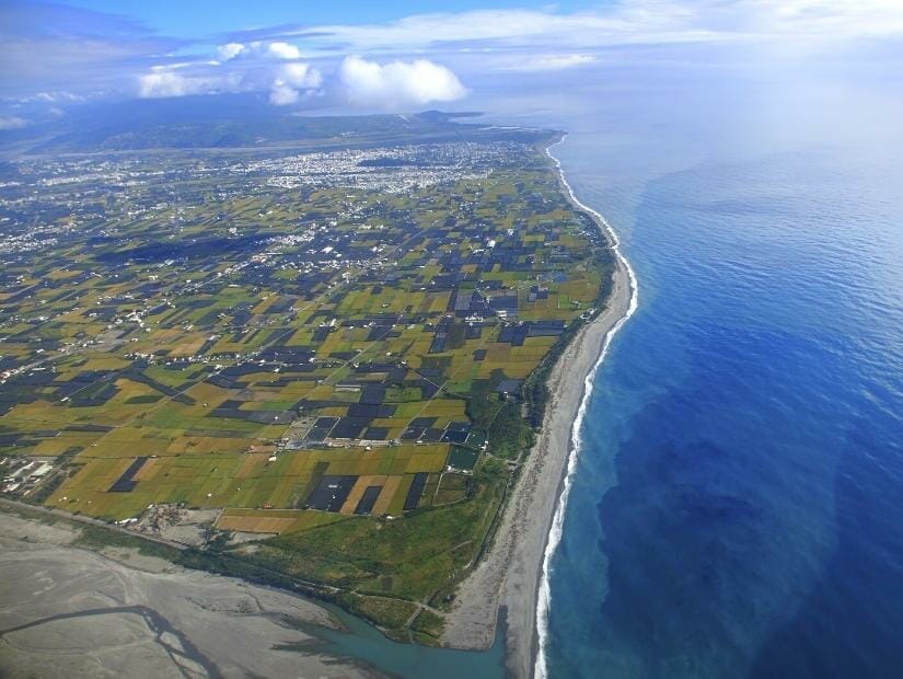 View of Taitung city taken from an airport, with the city, farm fields around it, and coastline with black sand beaches