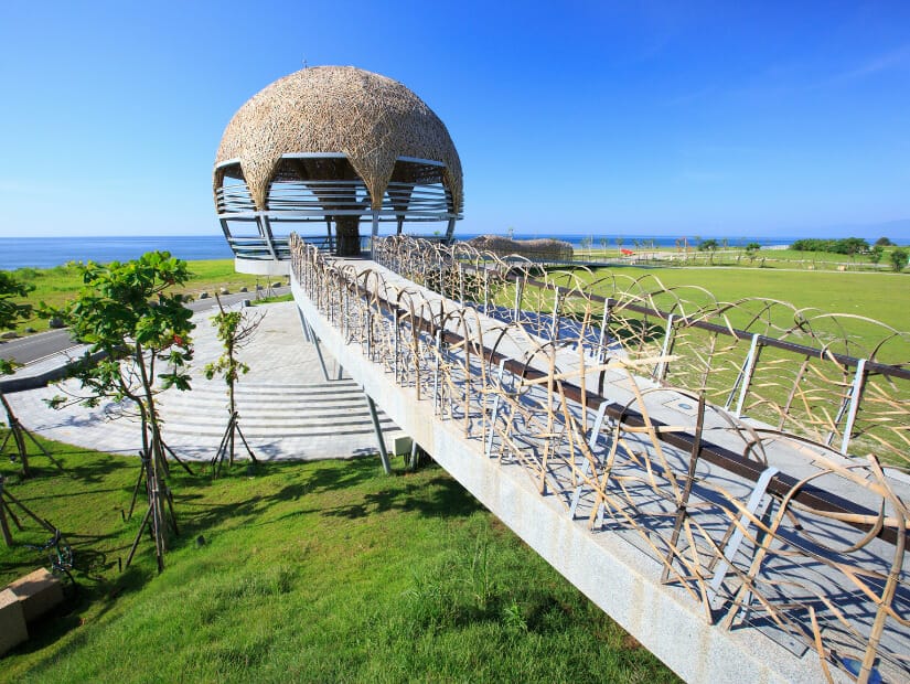 An elevated walkway leading to a famous Taiwanese bamboo artwork called Taitung Tree of Life in Taitung Seaside Park, with ocean in the background