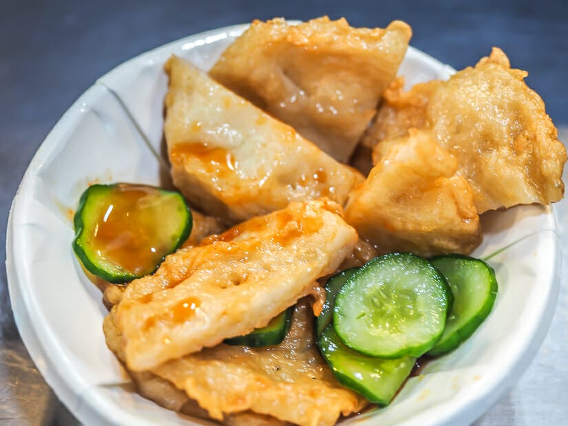 Close up of a small white paper bowl containing fish cakes and cucumber slices from Keelung Night Market