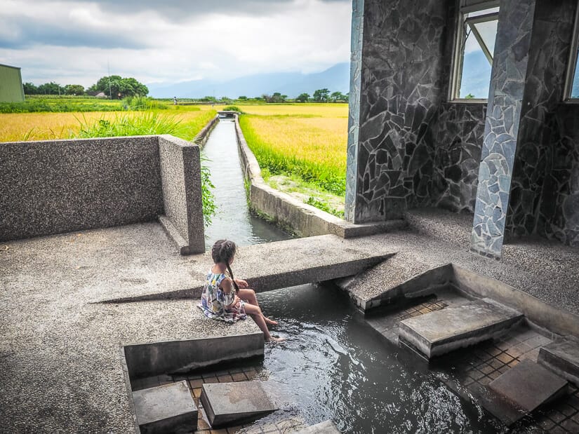 A girl dipping her feet in the water in  Jinyuen Laundry Pavillion in Chishang