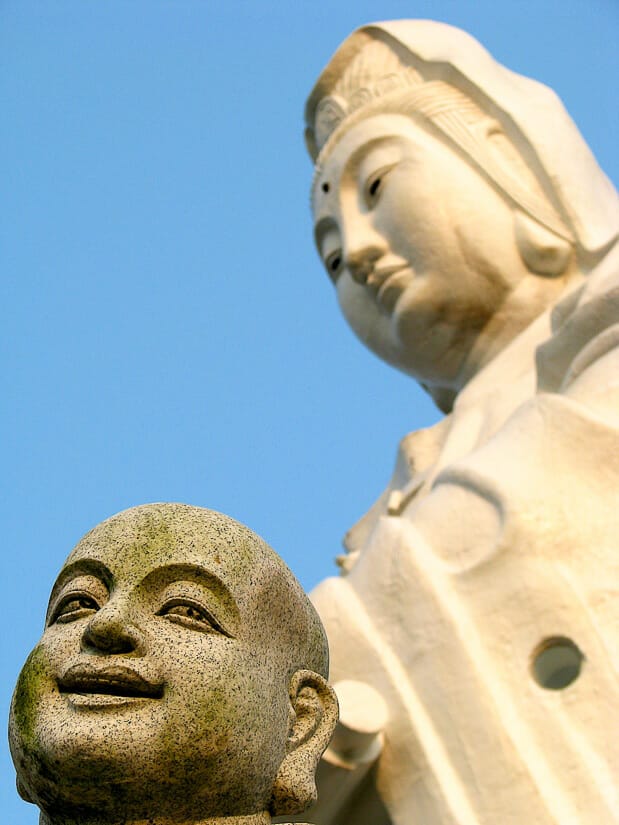Close up of a Buddha head, with giant white Guanyin statue in background shot at Zhongzheng Park in Keelung