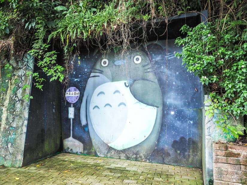 A painted mural of Totoro waiting at a bus stop painted on a wall in Keelung