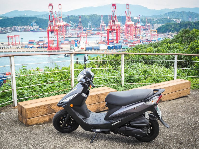 A scooter parked at a lookout point in Keelung, with Keelung port in the background