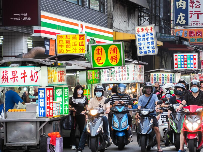 A row of scooters waiting at intersection in Zhonghua Road Night Market in Taichung