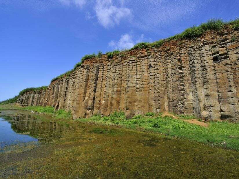 Basalt columns beside a pond of water at Daguoyue Columnar Basalt