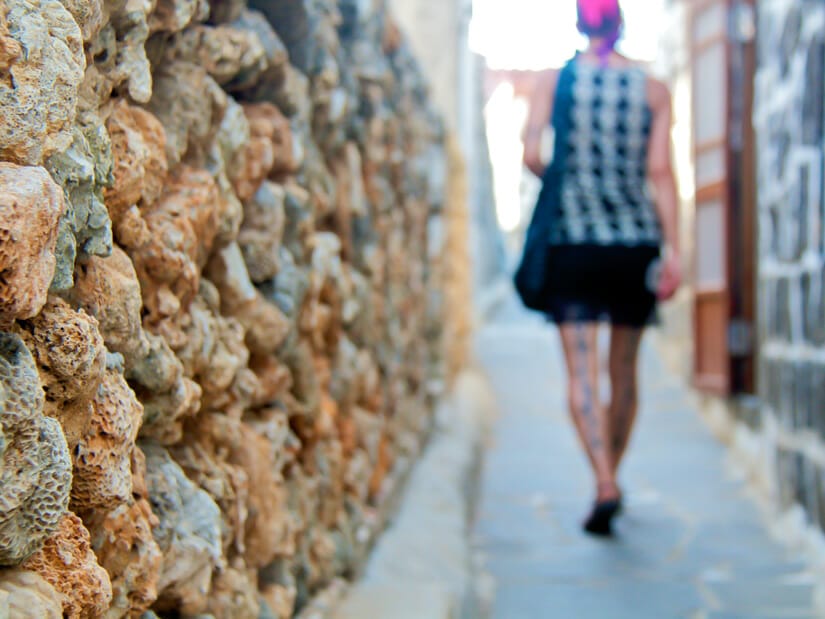 A woman walking past a coral wall in Erkan Historic Village