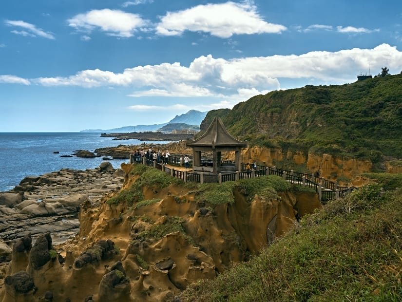 A pavilion on the coast of Taiwan with some visitors standing in it and admiring the view