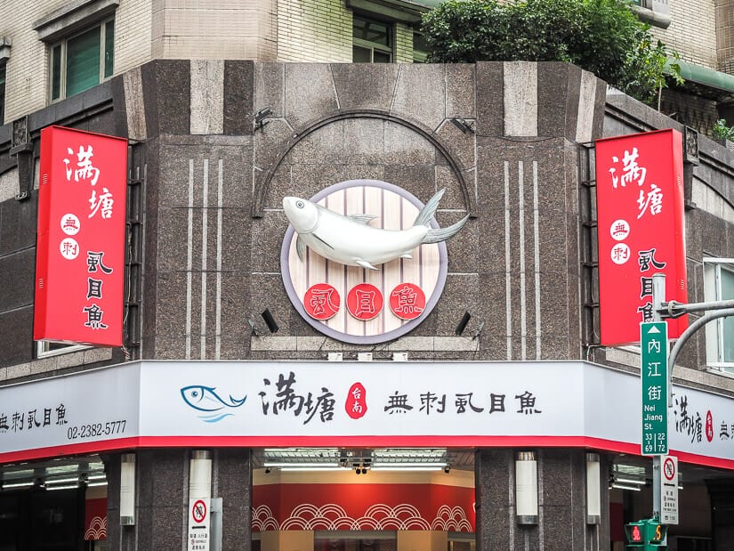 Exterior of a milkfish restaurant in Ximending, with a large fish statue hanging on the wall above the entrance