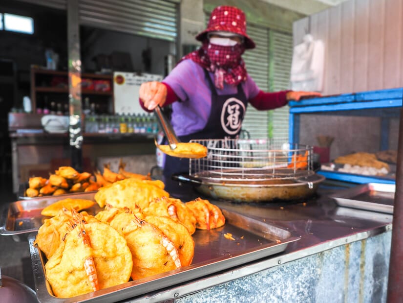 A old Taiwanese vendor serving fried fish from a food stall near Aimen beach and Lintou Beach