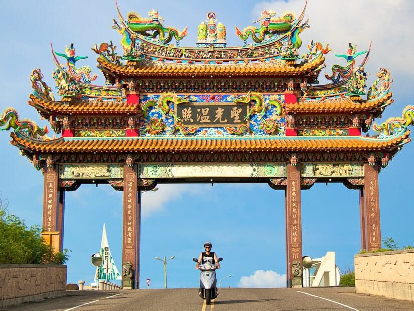 A man riding a scooter under a traditional Chinese gate on Penghu island