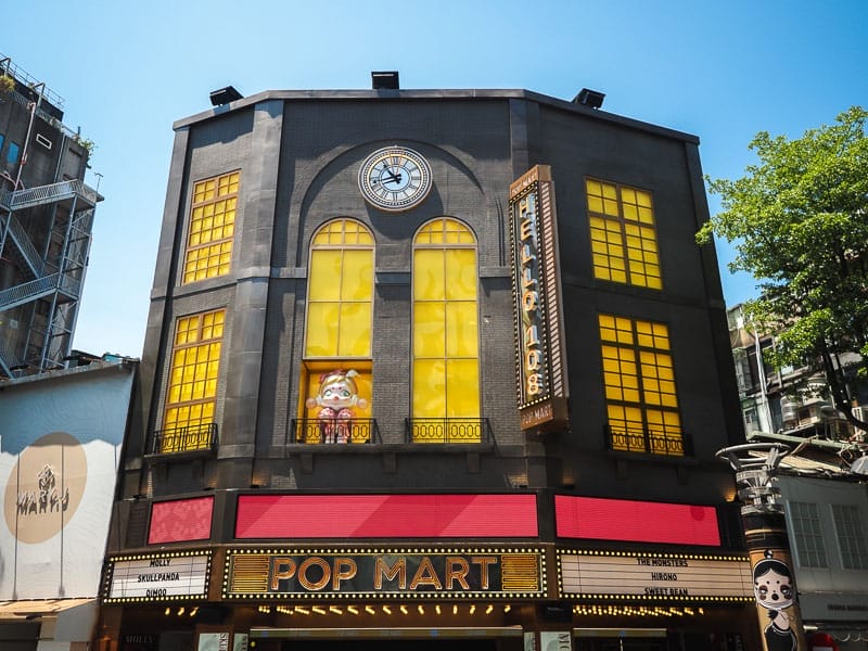 A large store front that says Pop Mart at the bottom, and at the top it looks like a traditional European style building with clock at the top