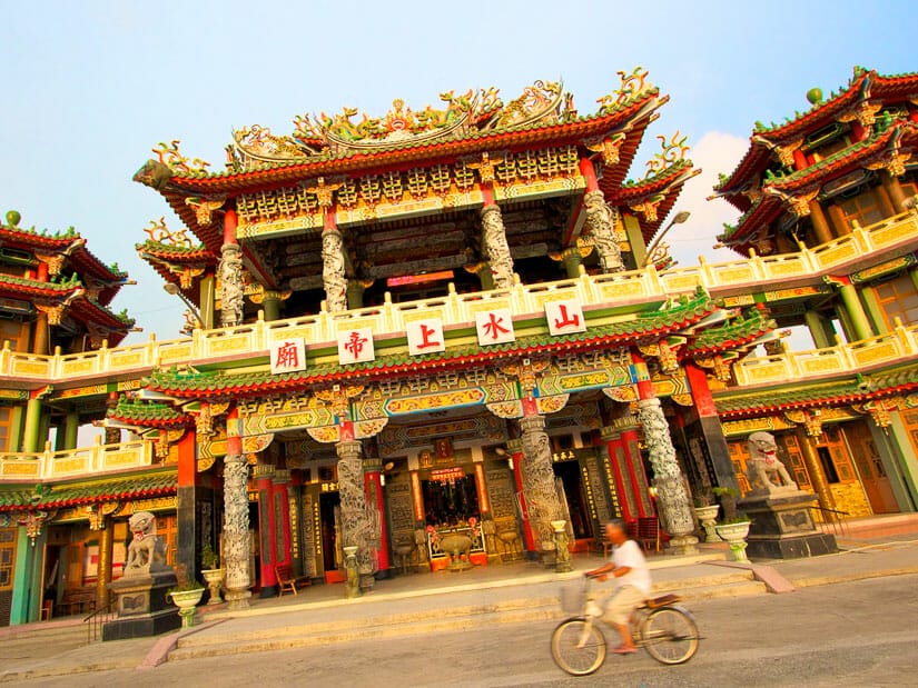 An elderly Taiwanese man riding a bicycle in front of a temple in Shanshui, Penghu