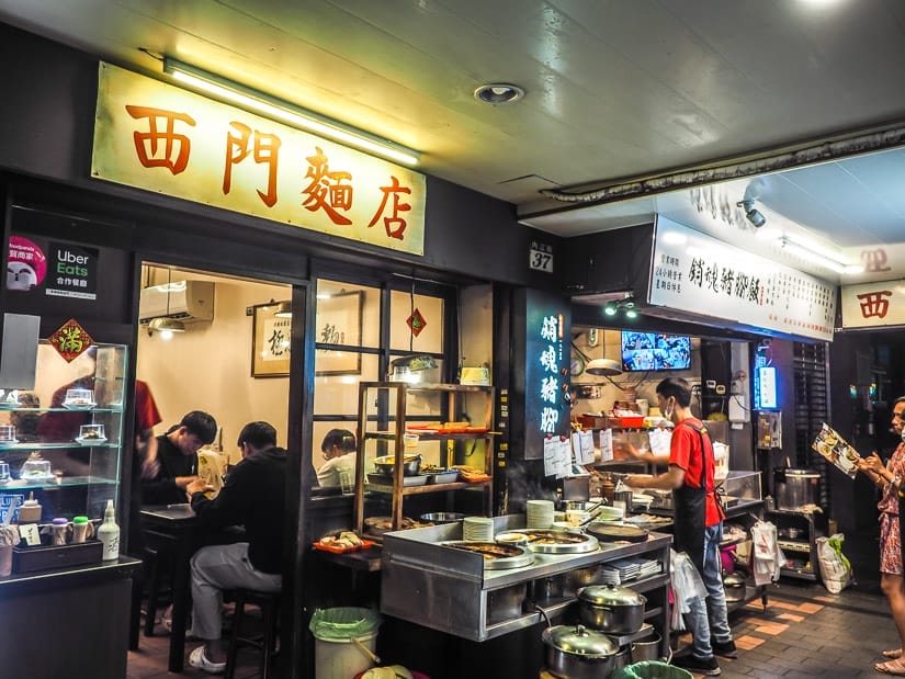 The outside of a small Taiwanese restaurant with cooks working out on the street