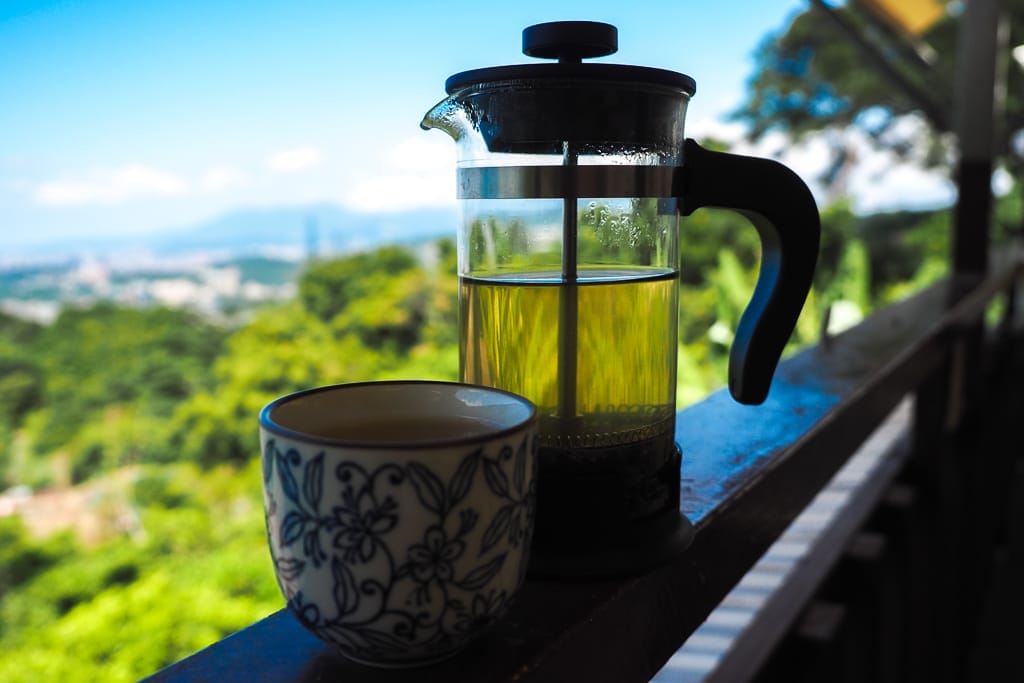 A pot of tea on a wooden railing with view of Taipei city