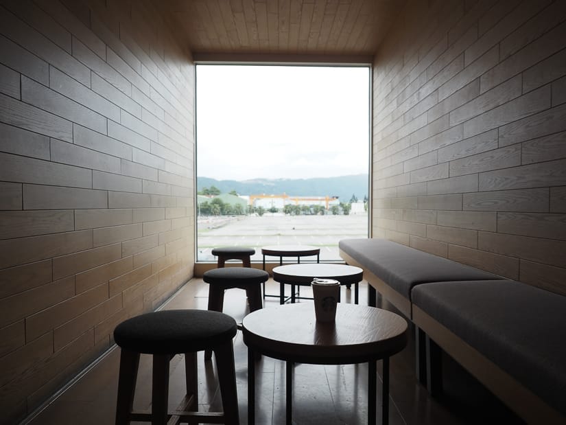 View from inside a shipping container turned Starbucks, with coffee on a small round table and chairs beside it