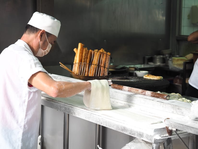 A Taiwanse breakfast cook prepares some dough for rolls on a counter in front of the kitchen