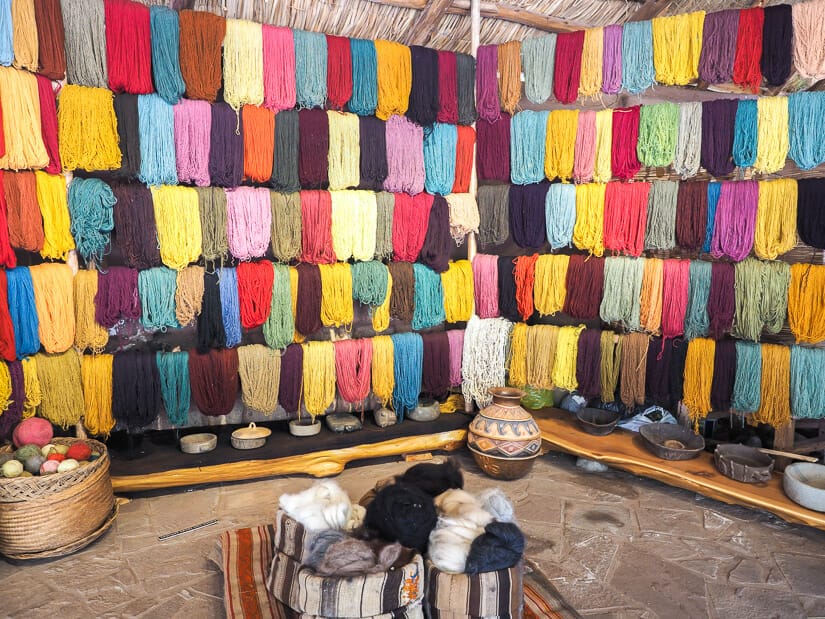 A wall with various colors of dyed llama yarn on display