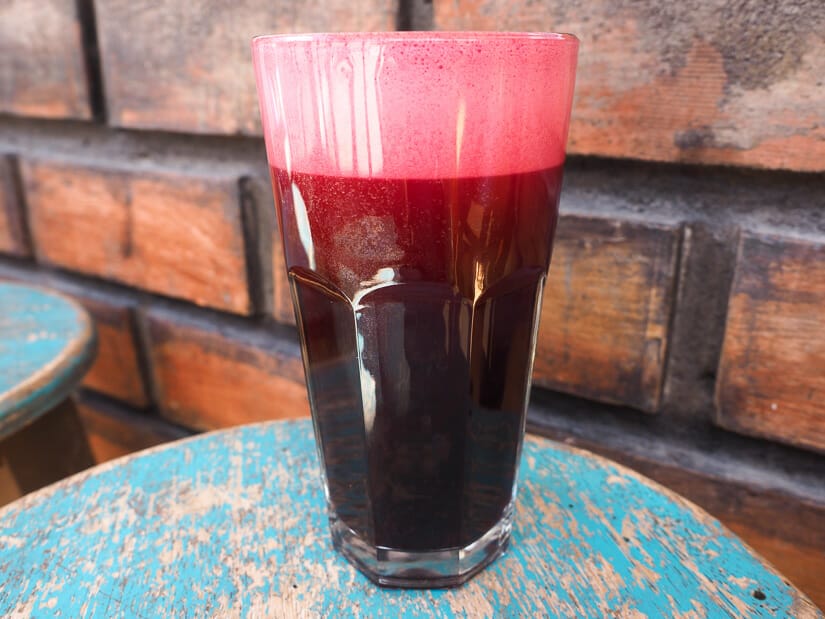 Close up of a large glass containing purple chicha morada drink on the  La Paila restaurant patio in Pisac
