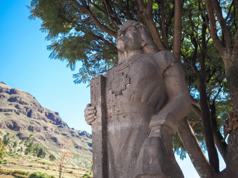 A statue of a clan leader in Pisac with tree and mountain behind it