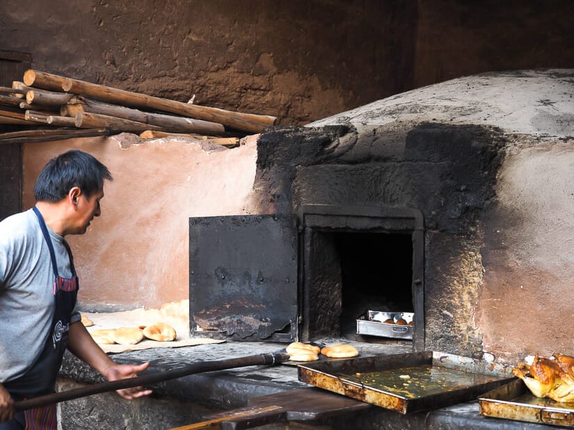 A man taking empanadas out of a traditional colonial oven in Pisac
