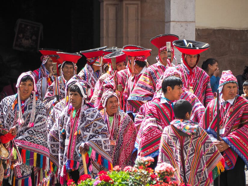 A group of very colorfully dressed indigenous people coming out of a church in Pisac