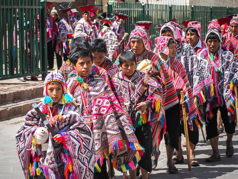 Indigenous children dressed in colorful clothing while parading out of the church in Pisac